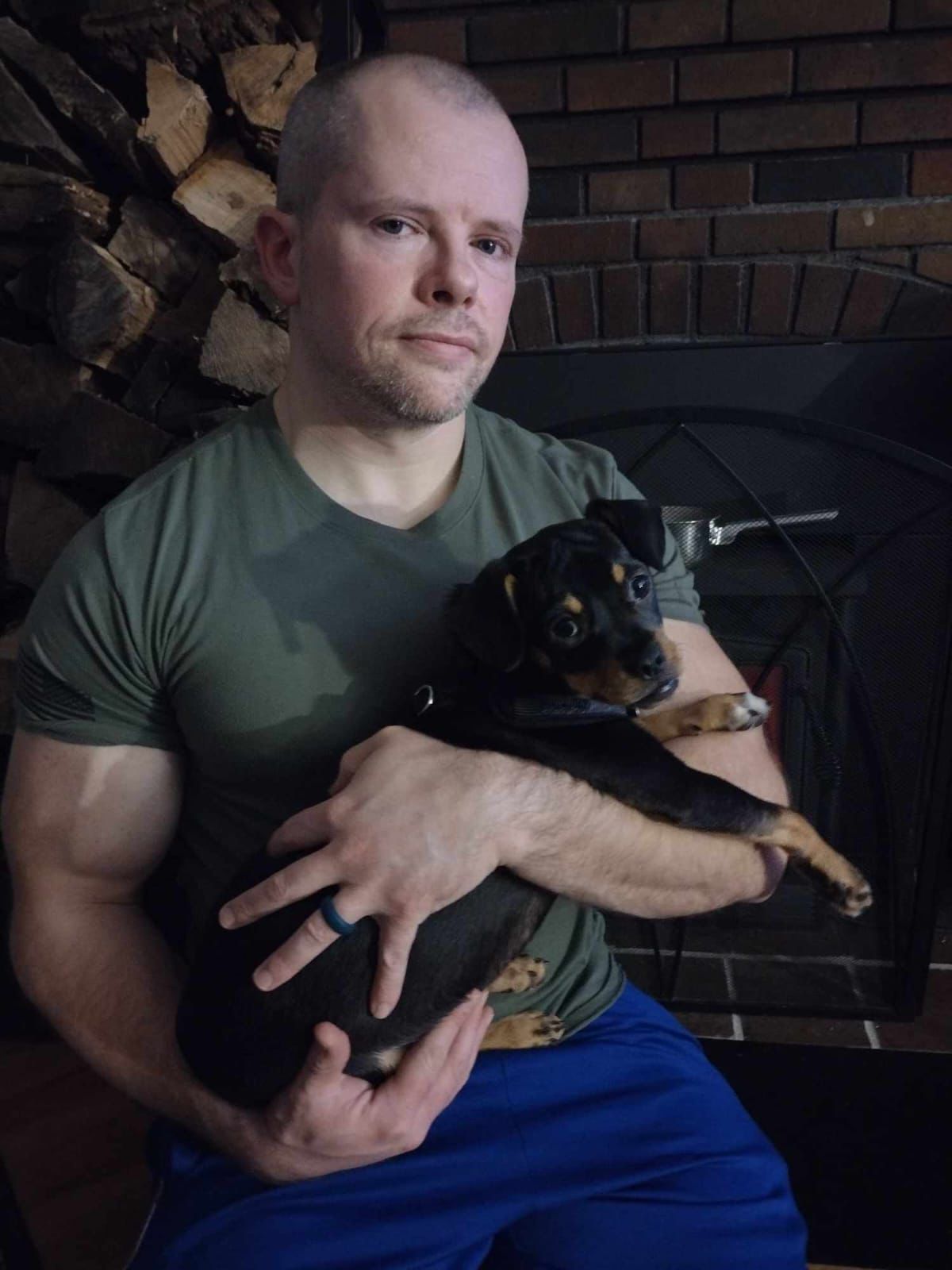Geoffrey Thayer holding a small dog indoors.